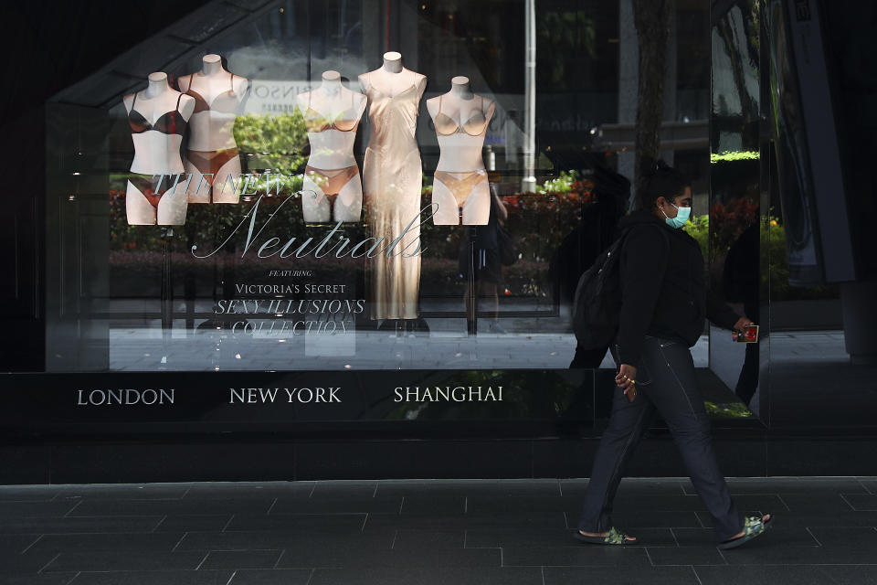 A woman wearing a protective face mask walks past a store along the Orchard Road shopping belt in Singapore, Friday, April 10, 2020. The Singapore government put in place "circuit breaker" measures in the light of a sharp increase of COVID-19 cases in recent days. Under the measures which will last through May 4, people have to stay home and step out only for essential tasks, such as going to work if they are in essential services, buying food and groceries, or for a short bout of exercise. (AP Photo/Yong Teck Lim)