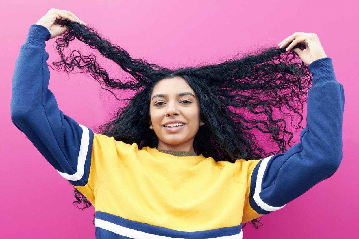 Young woman holding her hair wondering if silicones are bad for hair