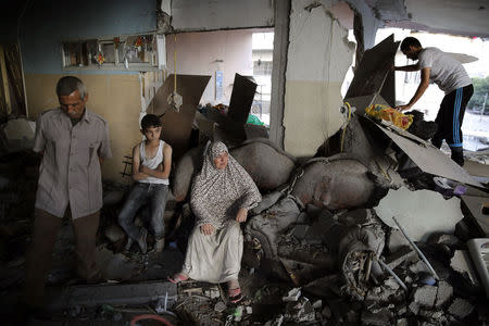 A Palestinian family gathers inside their damaged home, which police said was targeted in an Israeli air strike, in Gaza City July 17, 2014. REUTERS/Finbarr O'Reilly