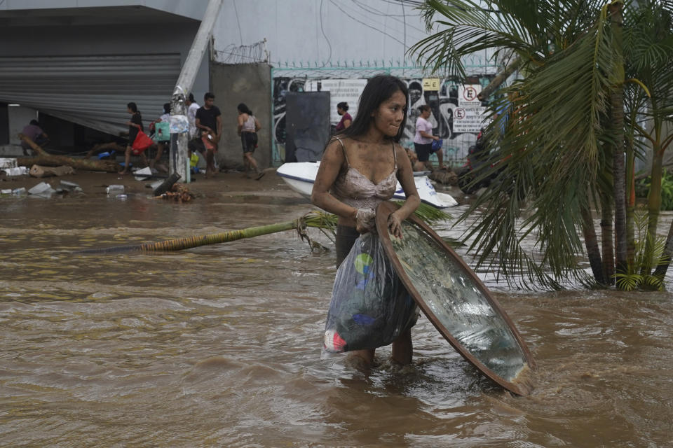 FILE - A woman walks away with stuff she took from a furniture store after Hurricane Otis ripped through Acapulco, Mexico, Wednesday, Oct. 25, 2023. Hurricane Otis turned from mild to monster in record time, and scientists are struggling to figure out how — and why they didn't see it coming. (AP Photo/Marco Ugarte, File)