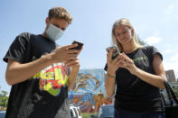 Maxwell Strome, left, and his friend Erica Dawson order food on their phones outside the R. House food hall, Wednesday, July 15, 2020, in Baltimore. The hall, which houses a variety of restaurants, has modified its seating areas as well as implementing an order and pay by phone system to ensure contactless transactions between restaurant operators and customers. (AP Photo/Julio Cortez)