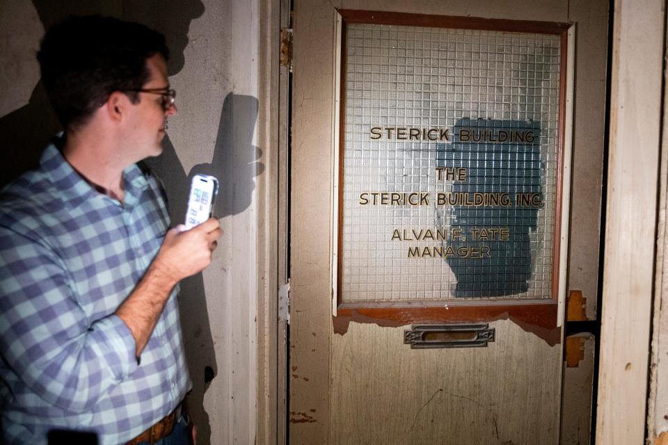 Stuart Harris, principal with Constellation Properties, shines his phone flashlight onto a door with “Sterick Building” signage visible on the glass during a tour of the building in Downtown Memphis, on Thursday, October 19, 2023.