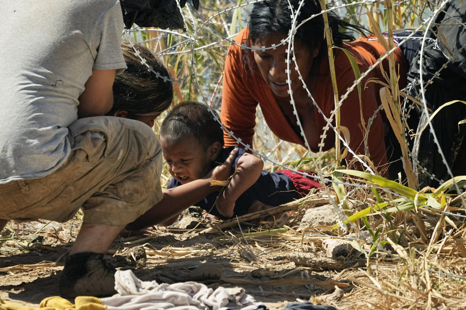 Migrants who crossed into the U.S. from Mexico pass under concertina wire along the Rio Grande river, on Sept. 21, 2023, in Eagle Pass, Texas. (AP Photo/Eric Gay)