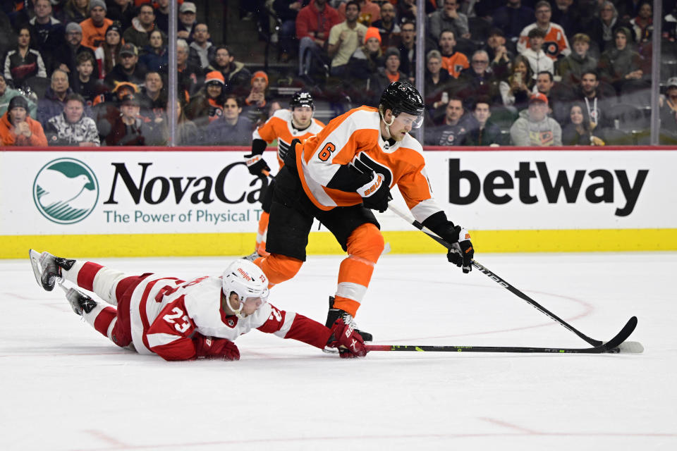 Philadelphia Flyers' Travis Sanheim (6) plays the puck past the reach of Detroit Red Wings' Lucas Raymond (23) during the second period of an NHL hockey game, Saturday, March 25, 2023, in Philadelphia. (AP Photo/Derik Hamilton)