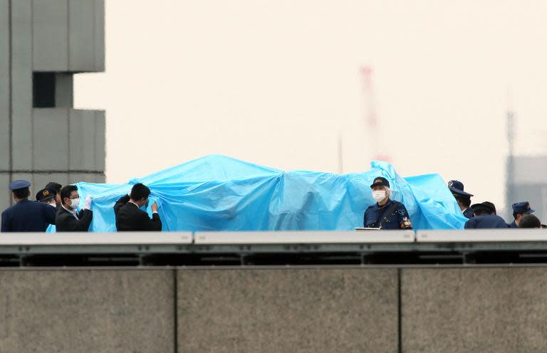 Police officers cover with a blue sheet and inspect a small drone, found on the roof of the Japanese prime minister's official residence in Tokyo, on April 22, 2015