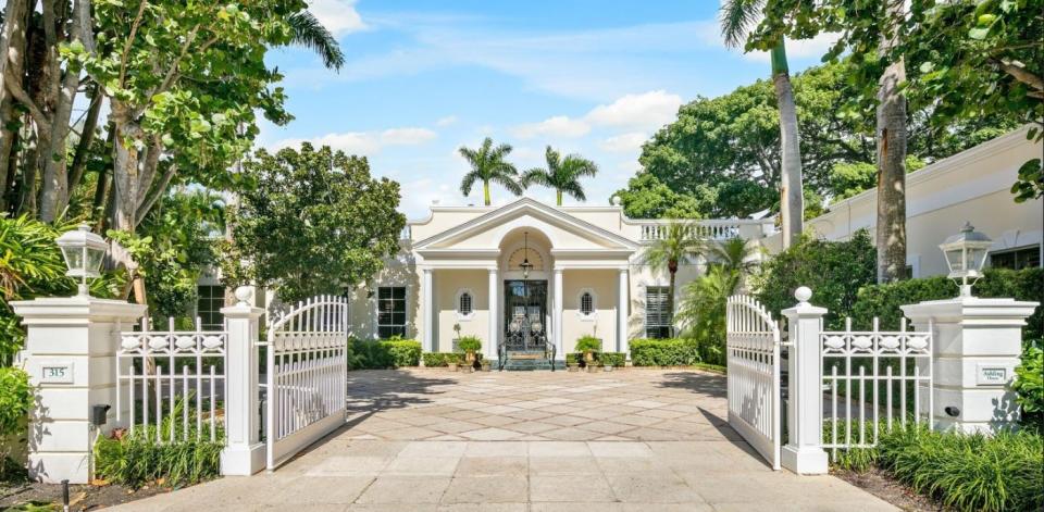 Gates open from a cul-de-sac to the driveway at 315 Chapel Hill Road, a Palm Beach lakefront estate just listed at $59.5 million.