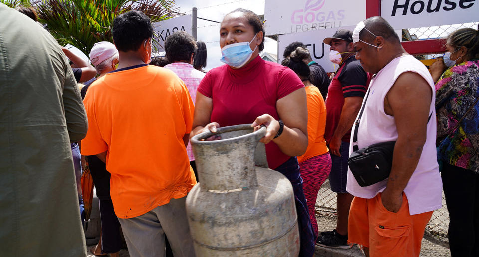 A woman carries a refilled gas container in the centre of the Tonga capital Nuku'alofa ahead of the country's first lockdown on February 2, 2022.