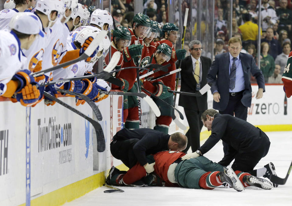 Medical personnel tend to Minnesota Wild defenseman Keith Ballard after he was injured on a check into the boards by New York Islanders left wing Matt Martin during the second period of an NHL hockey game in St. Paul, Minn., Tuesday, Dec. 9, 2014. (AP Photo/Ann Heisenfelt)