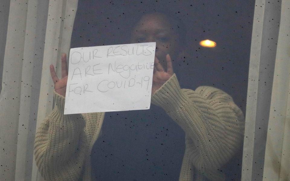 A woman holds up a sign for the media against the window at the Radisson Blu Edwardian Hotel -  Kirsty Wigglesworth/AP