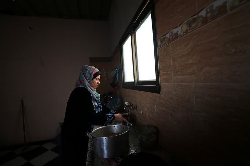 The wife of Palestinian man Eyad Al-Zahar works in their home kitchen in Gaza City