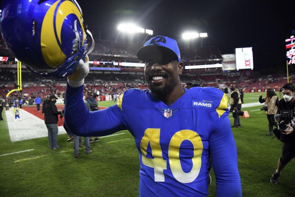 Rams outside linebacker Von Miller holds up his helmet near the field.