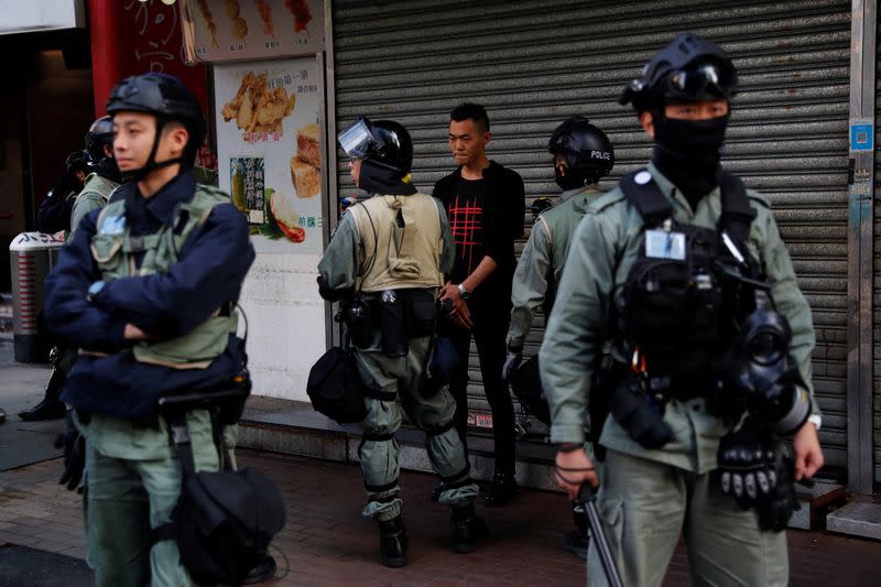 Riot police officers check the documents of a man outside Mong Kok station in Hong Kong