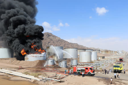 Firefighters try to cool down oil storage tanks adjacent to a tank engulfed by fire at the Aden oil refinery in Aden, Yemen January 12, 2019. REUTERS/Fawaz Salman