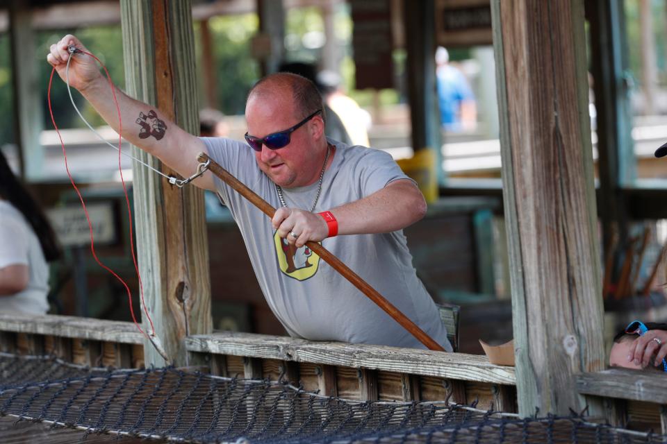 Michael Hoffman, 42, and his family feed fish to alligators at Gatorland in Orlando, Florida on June 25, 2024.