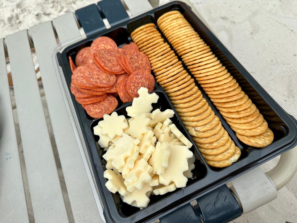 a tray of crackers, pepperoni, and cheese