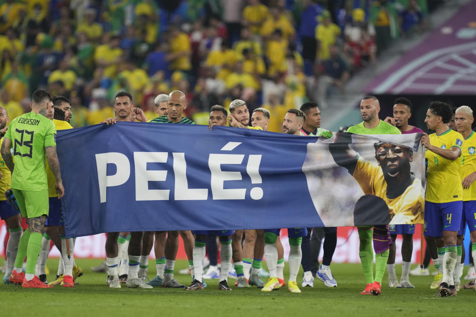 Brazilian players hold a banner in honour of the 82-year-old Brazilian soccer legend Pele who is in a hospital in San Paulo recovering from a respiratory infection at the end of the World Cup round of 16 soccer match between Brazil and South Korea at the Stadium 974 in Doha, Qatar, Monday, Dec. 5, 2022. (AP Photo/Jin-Man Lee)