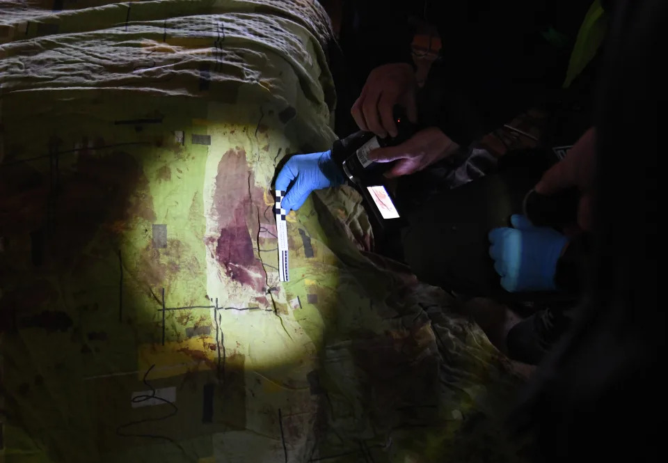 Blood-stained sheets are inspected in a home in Irpin, Ukraine, where the bodies of two men killed in an airstrike were found. 