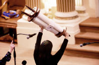 In this Saturday, Feb. 1, 2020, photo, Rabbi Jacqueline Mates-Muchin holds a Torah scroll aloft during Shabbat morning service at Temple Sinai in Oakland, Calif. Mates-Muchin says there’s extra worry as she feels obliged to be constantly mindful of her congregation’s safety. Since the Pittsburgh massacre, she said, “I don’t begin a service without having a rough plan of where I’d direct people if someone came in with a gun.” (AP Photo/Noah Berger)