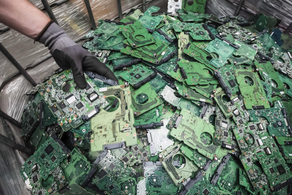 In this photo taken on July 13, 2018, a worker throws components of electronic elements into a bin at the Out Of Use company warehouse in Beringen, Belgium. Out Of Use dismantles computer, office and other equipment and recuperates an average of around 90 percent of the raw materials from electronic waste. (AP Photo/Geert Vanden Wijngaert)