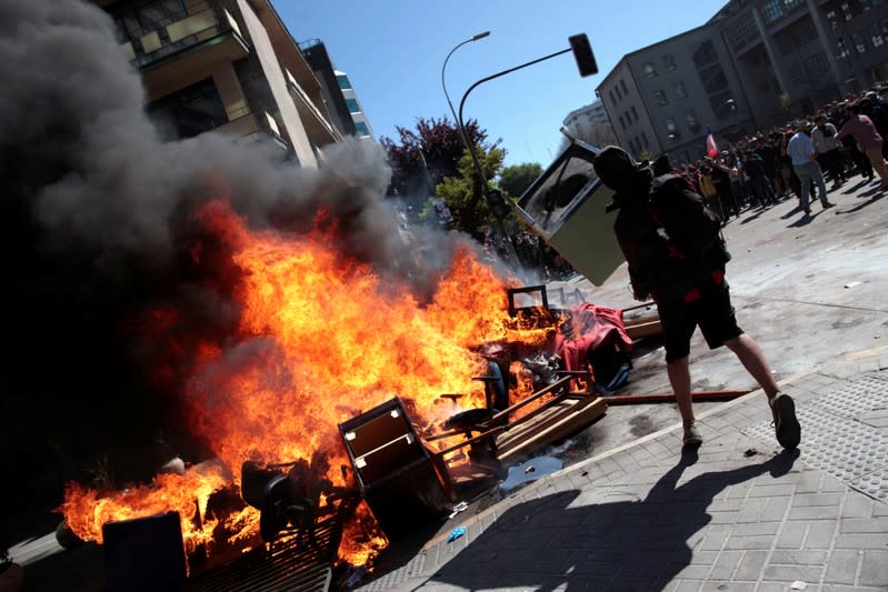 A demonstrator throws a furniture onto burning barricade during a protest against Chile's state economic model in Concepcion