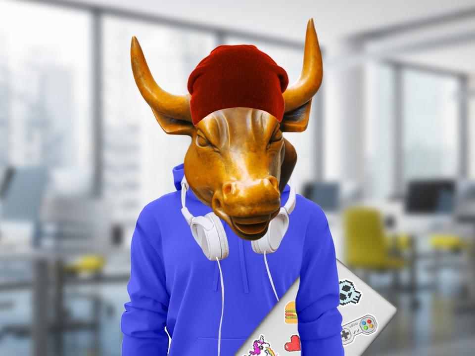 The wall street bull in a hoodie and headphones, holding a laptop with stickers on it.