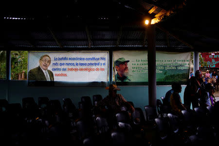 Images of Cuban President Raul Castro (L) and late Cuban President Fidel Castro (R) are displayed inside a community center during the recording of an episode of the popular TV show "Palmas y Canas" in the village of Providencia, in the Sierra Maestra, Cuba, March 29, 2018. REUTERS/Alexandre Meneghini