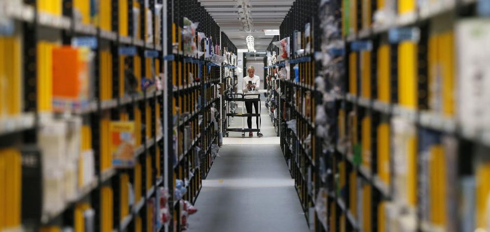 A member of staff pushes a trolley as she collects orders at the Amazon fulfilment centre in Peterborough