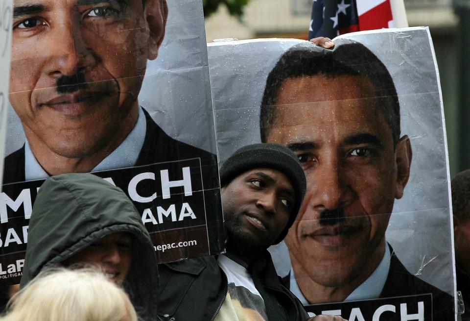 A member of the Tea Party movement holds posters of President Barack Obama depicted with a Hitler mustache during a protest in San Francisco in 2010.