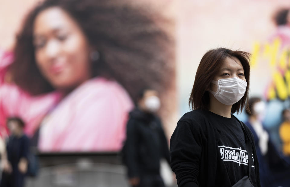 A woman wearing a face mask waits for the traffic lights to change at the famed Shibuya crossing in Tokyo on Thursday, May 20, 2021. (AP Photo/Hiro Komae)