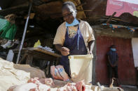 In this photo taken Thursday, June 4, 2020, Margaret Awino, 54, who lost her job after 15 years as a cleaner for a charity, prepares raw chicken to fry in the street to earn some income, in the Kibera slum, or informal settlement, of Nairobi, Kenya. Factories and stores are reopening and economies are reawakening but many jobs just aren't coming back - that's the harsh truth facing workers laid off because of the coronavirus around the U.S. and the world. (AP Photo/Khalil Senosi)