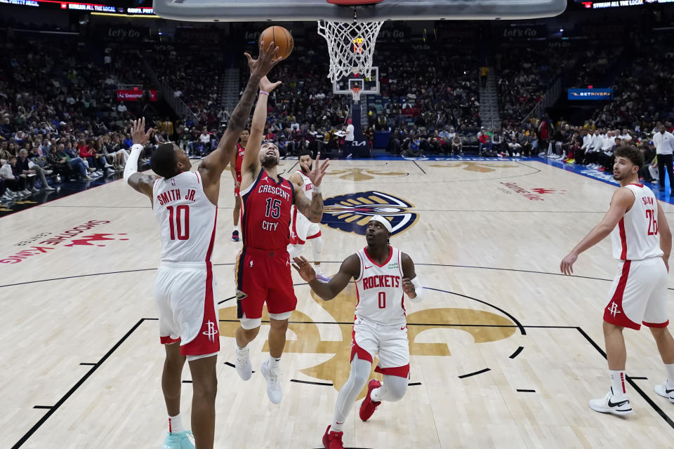 New Orleans Pelicans guard Jose Alvarado (15) shoots between Houston Rockets forward Jabari Smith Jr. (10) and guard Aaron Holiday (0) in the first half of an NBA basketball game in New Orleans, Saturday, Dec. 23, 2023. (AP Photo/Gerald Herbert)