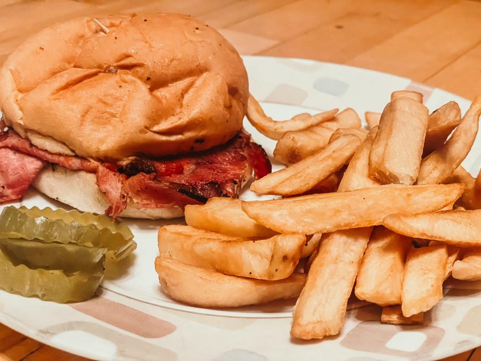 pulled pork sandwich, pickles, and thick french fries on a kitchen plate