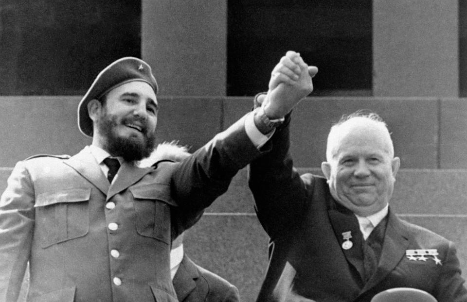 FILE - Cuba's leader Fidel Castro, left, and Nikita Khrushchev, Soviet premier and the First Secretary of the Communist Party of the Soviet Union clasp hands at the Lenin mausoleum in Moscow's Red Square on May Day in Moscow, Russia in May 1, 1963. Many observers say the closest that the world has come to full nuclear war was in the 1962 confrontation between the United States and the USSR over the presence in Cuba of Soviet nuclear missiles, which Khrushchev sent in response to the US placing nuclear-capable missiles in Turkey. (TASS via AP, File)