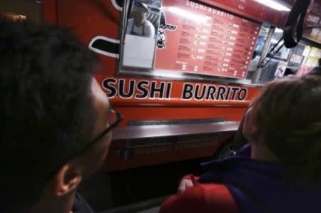 People stand in line to order from the Sushi Burrito food truck during the monthly first Friday event on Abbot Kinney Boulevard in Venice, California November 7, 2014. REUTERS/Jonathan Alcorn