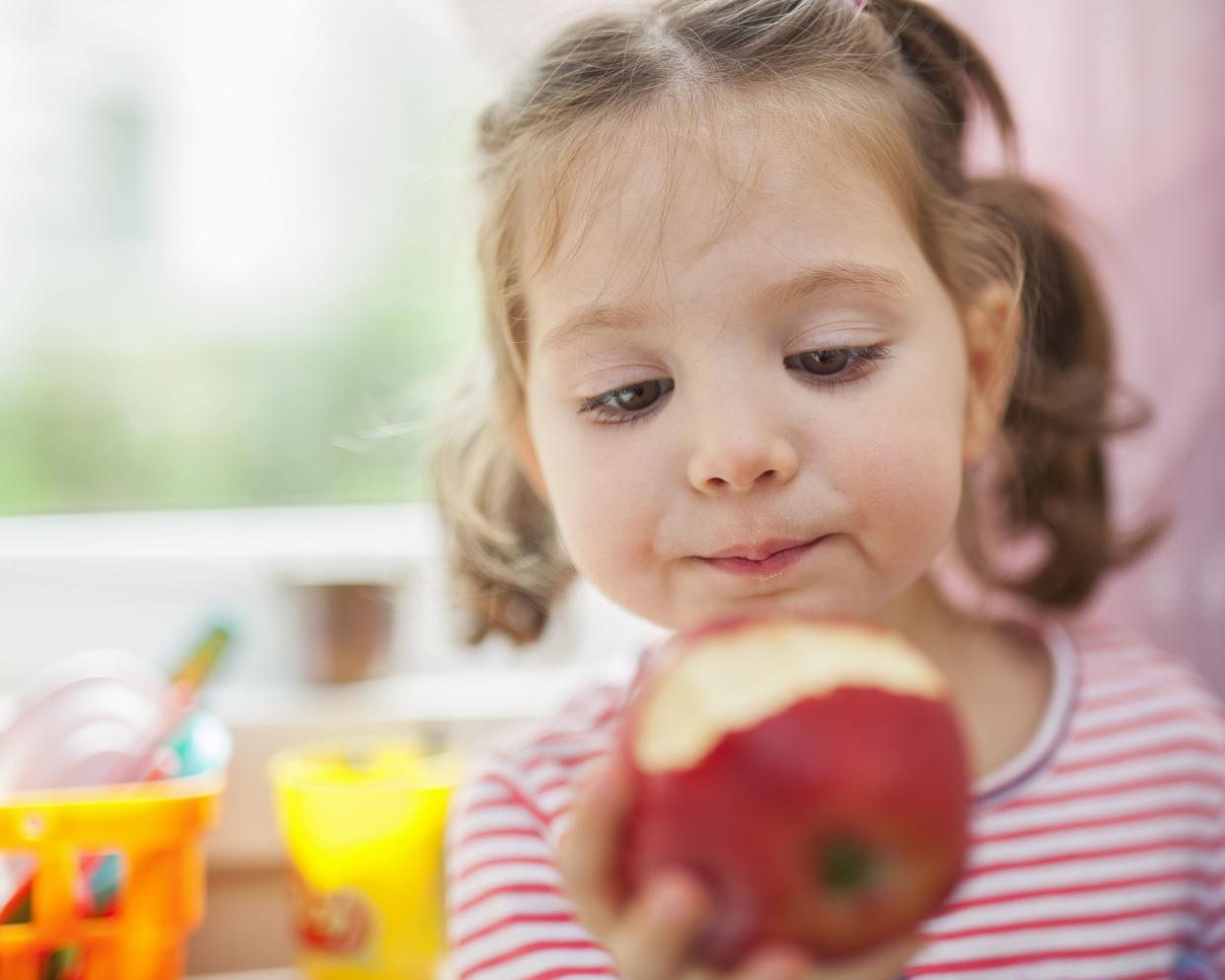 closeup photograph of little cute girl eating apple