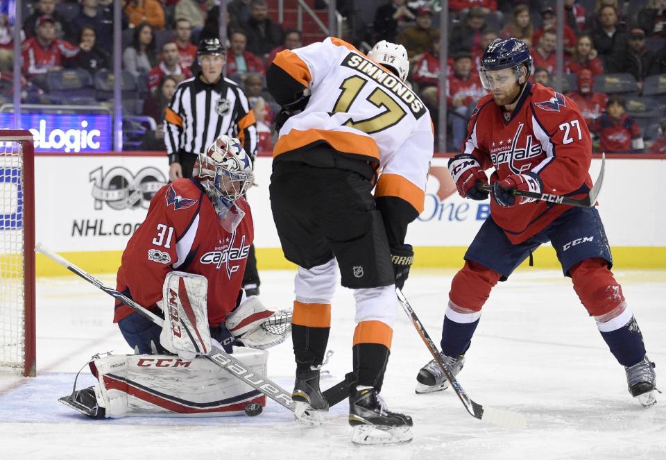 Washington Capitals goalie Philipp Grubauer (31), of Germany, stops the puck against Philadelphia Flyers right wing Wayne Simmonds (17) during the second period of an NHL hockey game, Sunday, Jan. 15, 2017, in Washington. Capitals defenseman Karl Alzner (27) looks on. (AP Photo/Nick Wass)