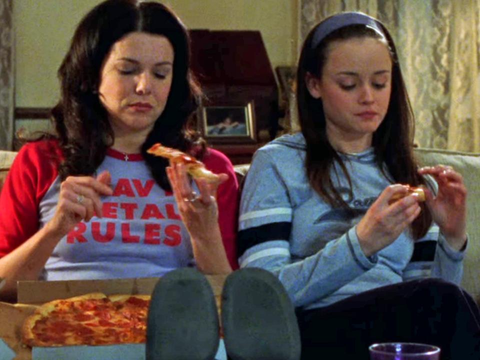 lorelai and rory eating pizza on the couch on an episode of gilmore girls