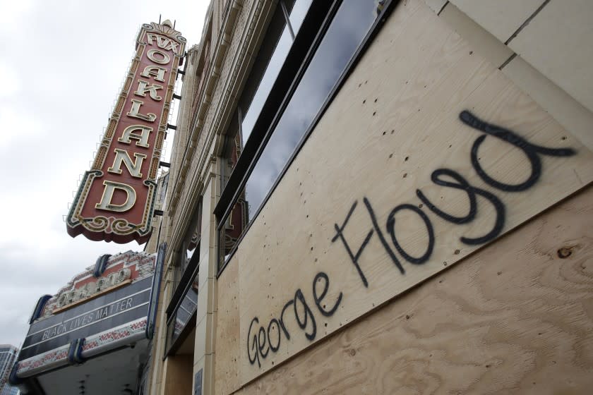 The name George Floyd is shown written on a boarded up window to the Fox Theater after protests in Oakland, Calif., Saturday, May 30, 2020. Protests across the country have escalated over the death of George Floyd who died after being restrained by Minneapolis police officers on Memorial Day, May 25.(AP Photo/Jeff Chiu)