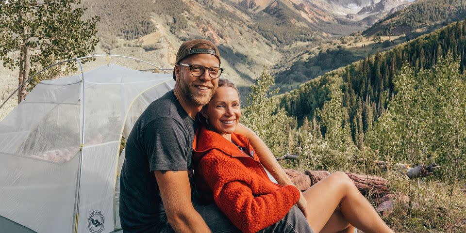 sarah herron, husband, and dog in front of woodsy, mountainous landscape