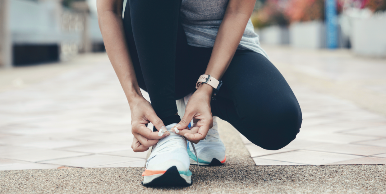 a person kneeling on the ground tying shoes up