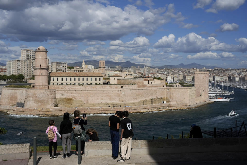 People stand in the gardens overlooking the Old Port, in Marseille, southern France, Tuesday, May 7, 2024. The Olympic torch will finally enter France when it reaches the southern seaport of Marseille on Wednesday. (AP Photo/Thibault Camus)