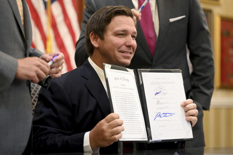 Florida Gov. Ron DeSantis holds up a bill allowing the import of cheaper prescription drugs from other countries after signing it, Tuesday, June 11, 2019, at the Eisenhower Recreation Center in The Villages, Fla. (Max Gersh/Daily Sun via AP)