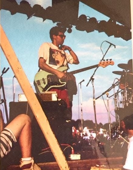 Bass guitarist Juan Molina in a 1980s photo pausing on stage during an outdoor concert.