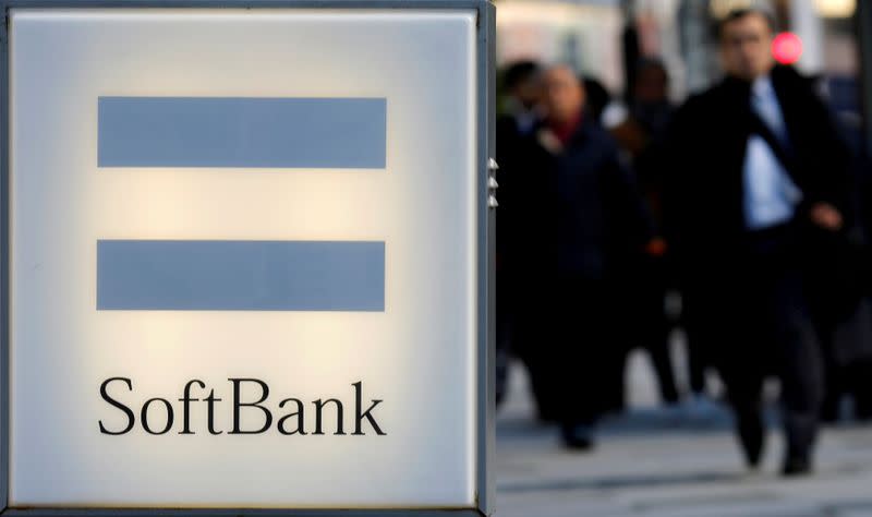 FILE PHOTO: People walk behind the logo of SoftBank Corp in Tokyo