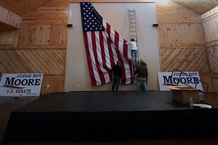 Workers hang a U.S. flag inside a venue where Republican Senate candidate Roy Moore will hold a rally in Midland City, Alabama, U.S., December 11, 2017. REUTERS/Carlo Allegri