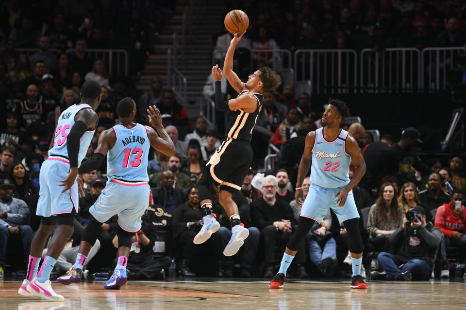 Atlanta Hawks guard Trae Young, second from right, shoots between Miami Heat forward Bam Adebayo (13) and forward Jimmy Butler (22) during the second half of an NBA basketball game Thursday, Feb. 20, 2020, in Atlanta. (AP Photo/John Amis)