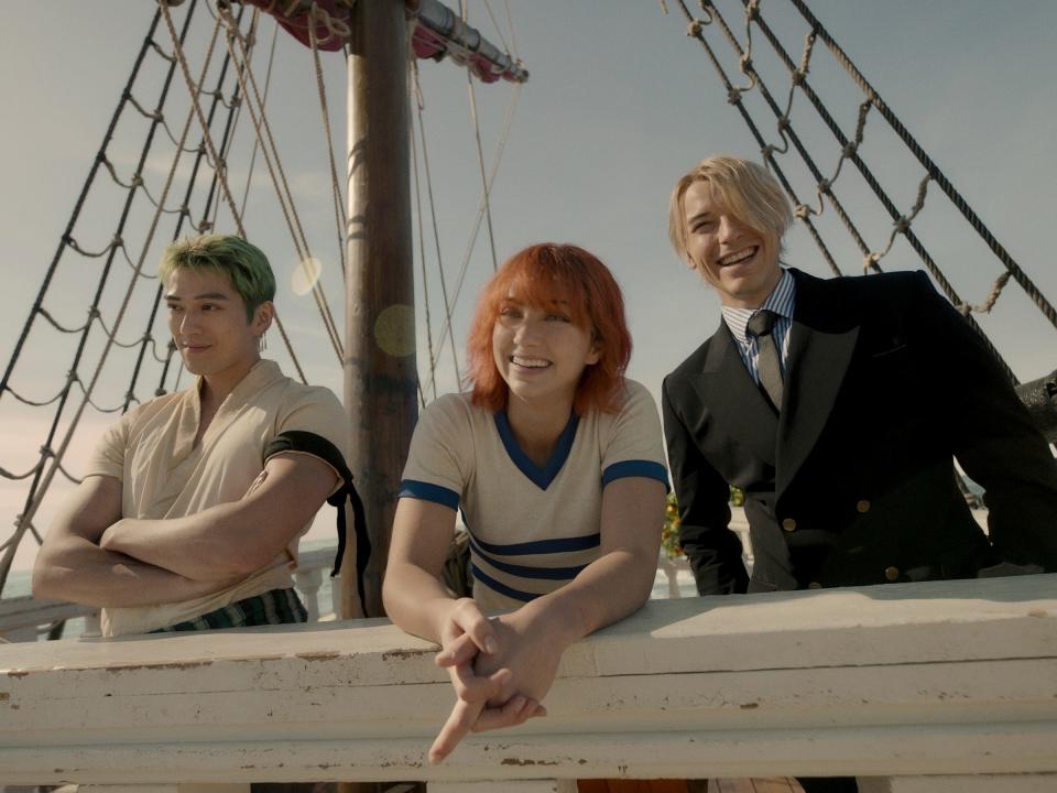 zoro, nami, and sanji in the one piece live action, leaning against the rail of the ship, and looking fondly ahead