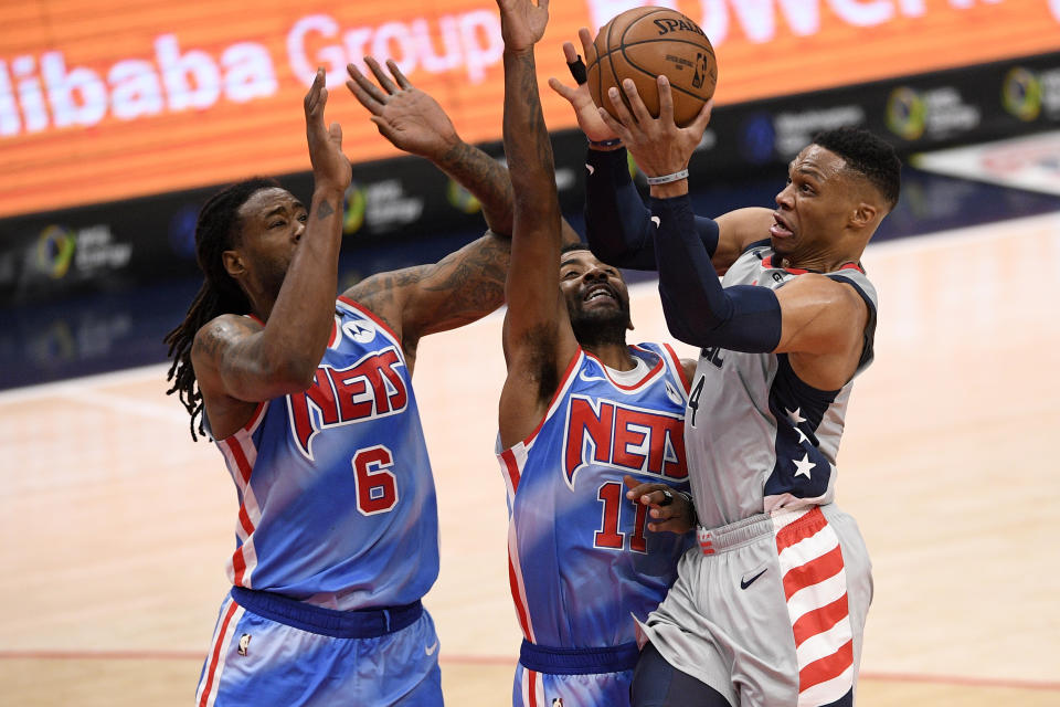 Washington Wizards guard Russell Westbrook, right, goes to the basket against Brooklyn Nets guard Kyrie Irving (11) and center DeAndre Jordan (6) during the first half of an NBA basketball game, Sunday, Jan. 31, 2021, in Washington. (AP Photo/Nick Wass)