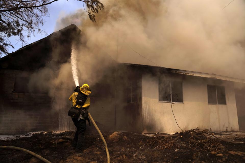 A firefighter works to save a home during the Fairview Fire in Hemet, California, US, on Tuesday, Sept. 6, 2022. In Southern California, two people were killed and one injured by the Fairview Fire, which started Monday near the city of Hemet, the Riverside County Fire Department said.