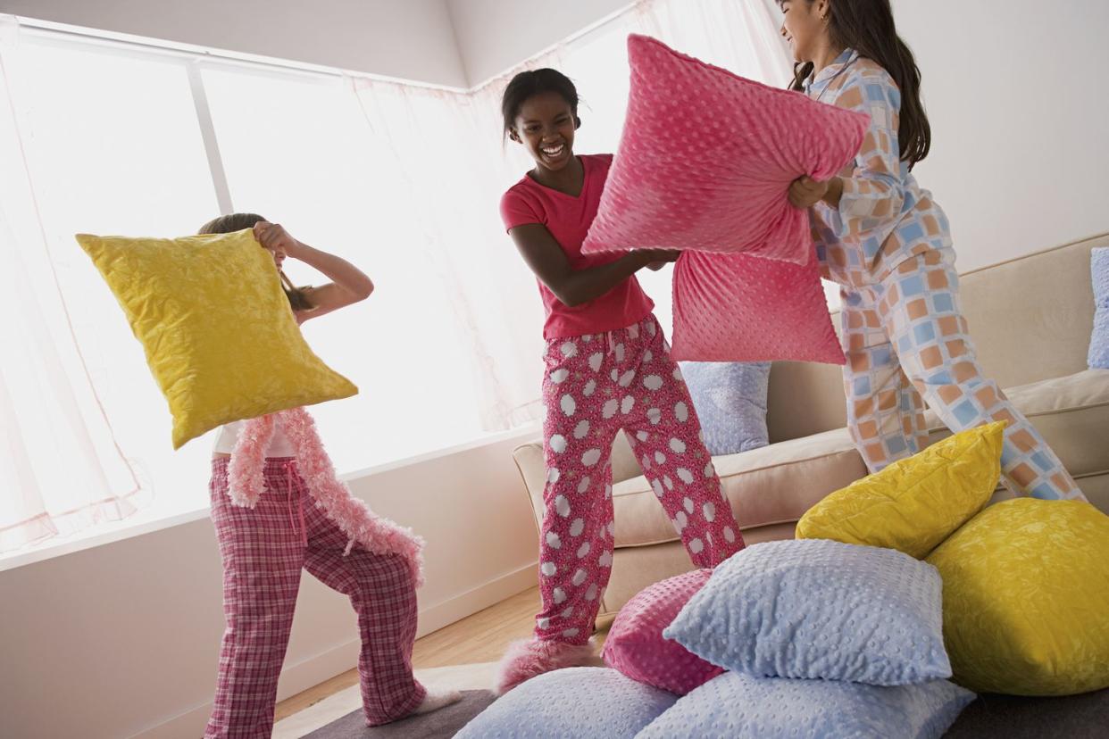 usa, california, los angeles, three girls 10 11 having pillow fight at slumber party